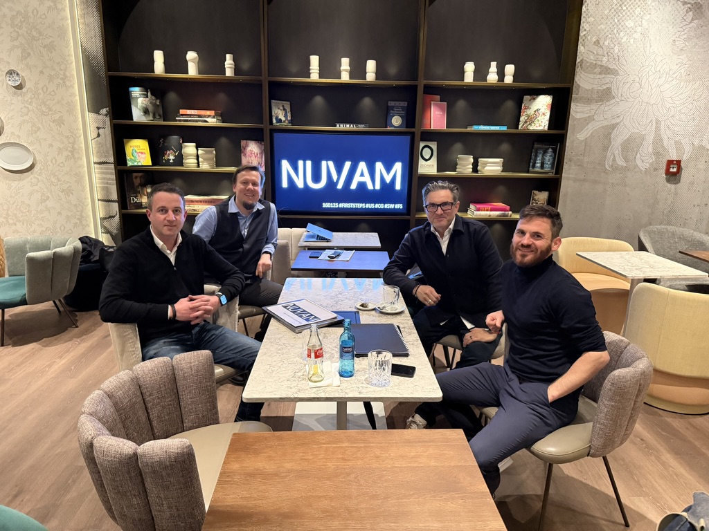 Four people around a table in Dresden, with NUWAM displayed on the screen behind them